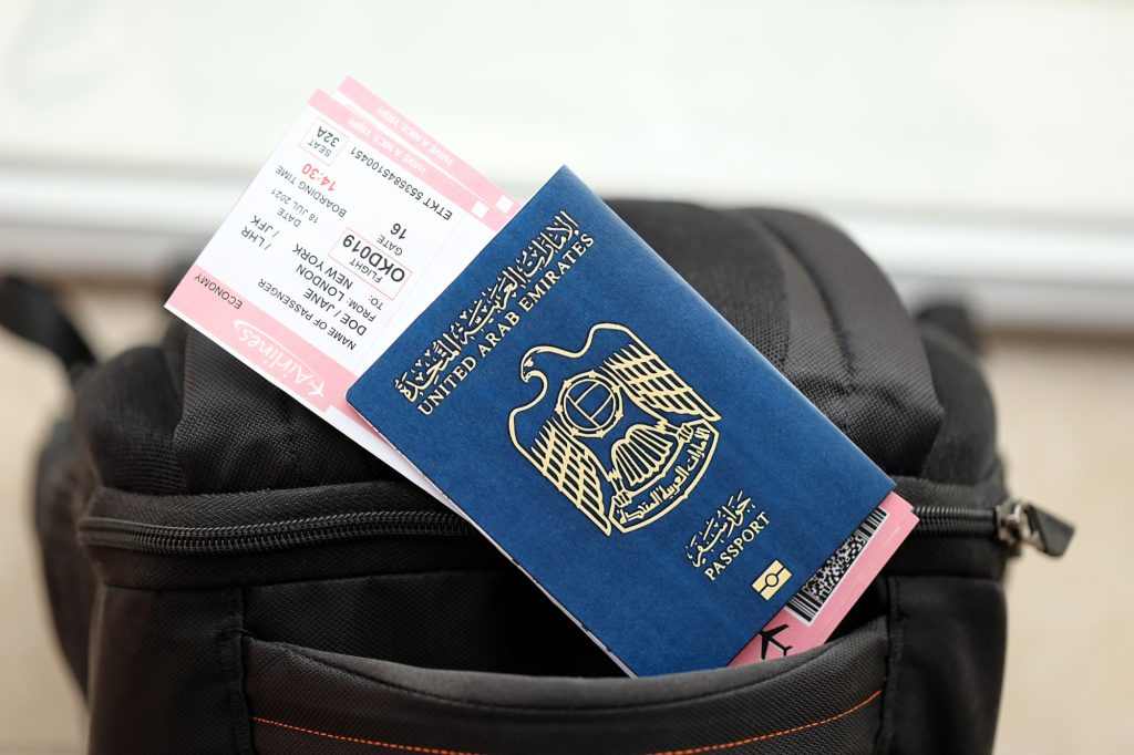 Blue United Arab Emirates passport with airline tickets on touristic backpack